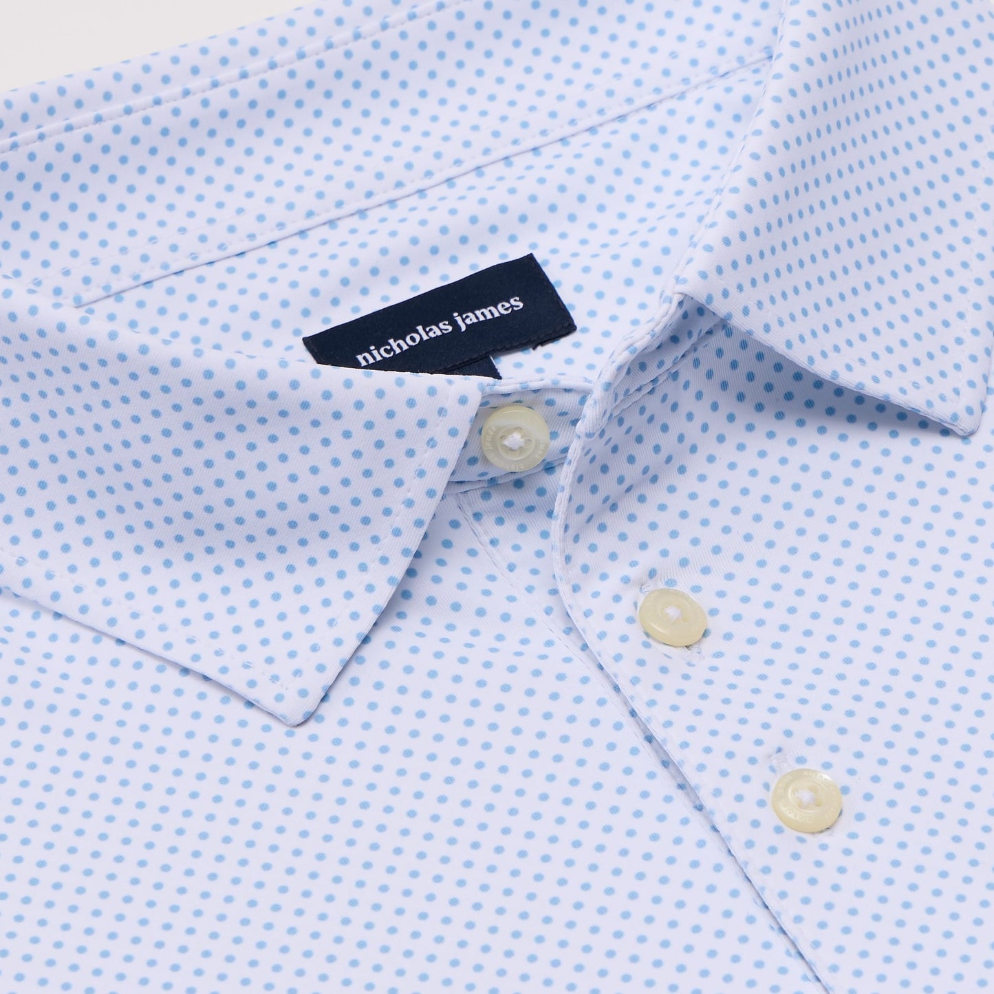 Close-up of a light blue pin dot shirt with a 'Nicholas James' label.