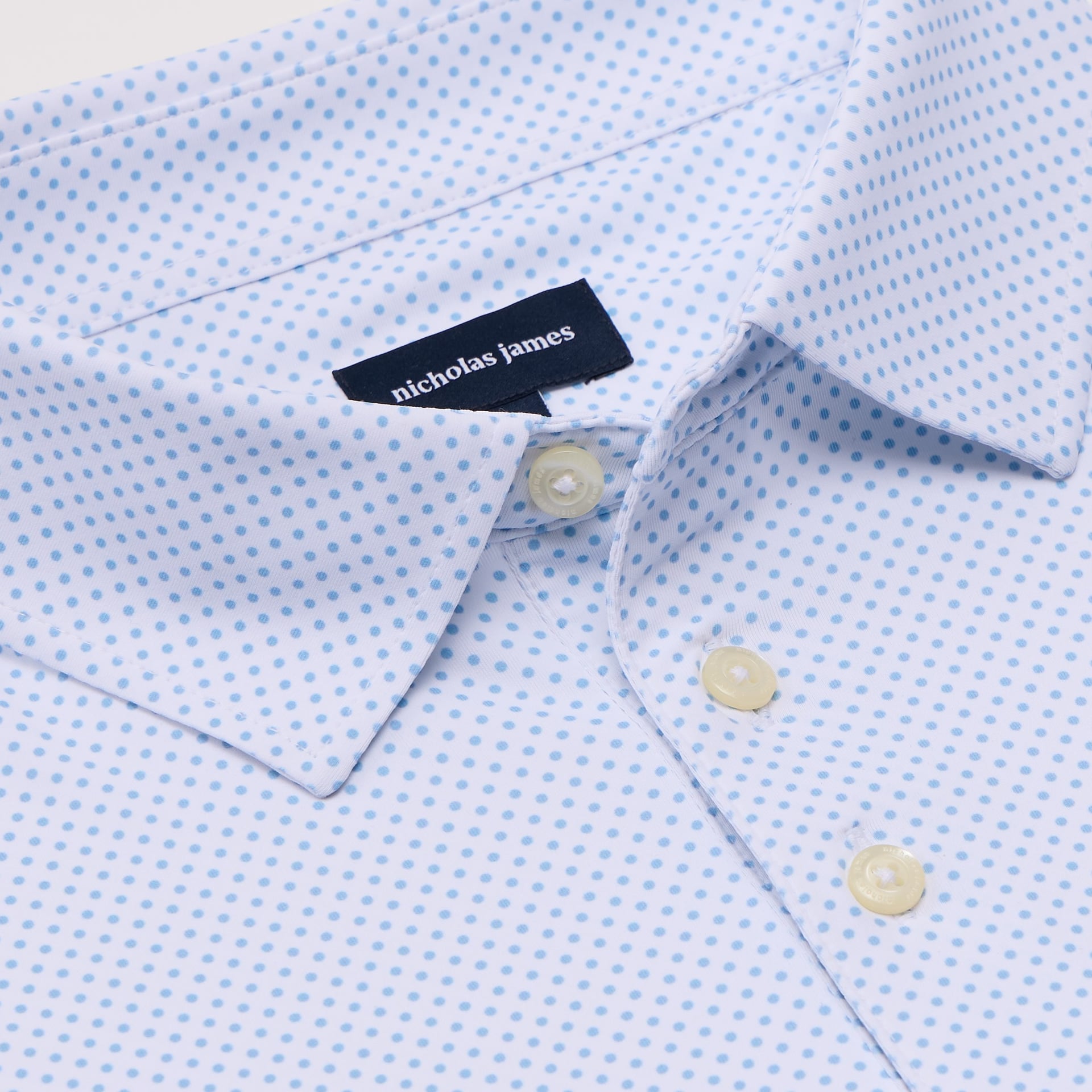 Close-up of a light blue pin dot shirt with a 'Nicholas James' label.