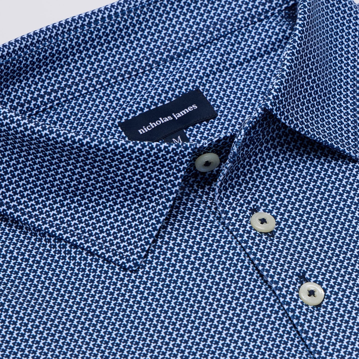 Close-up of a blue patterned shirt with 'nicholas james' label.