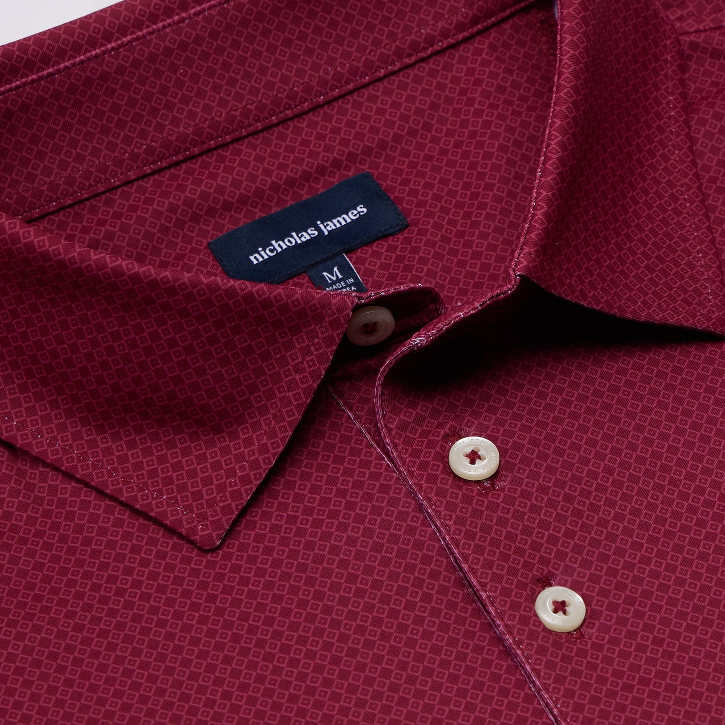 Close-up of a maroon shirt with a 'Nicholas James' label and buttons.
