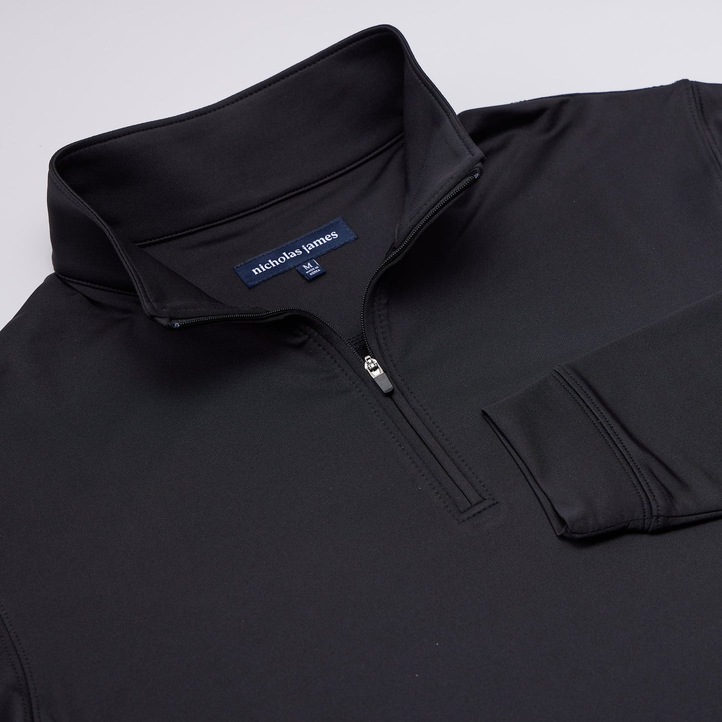 Black quarter-zip sweatshirt with nicholas james logo on a light gray background