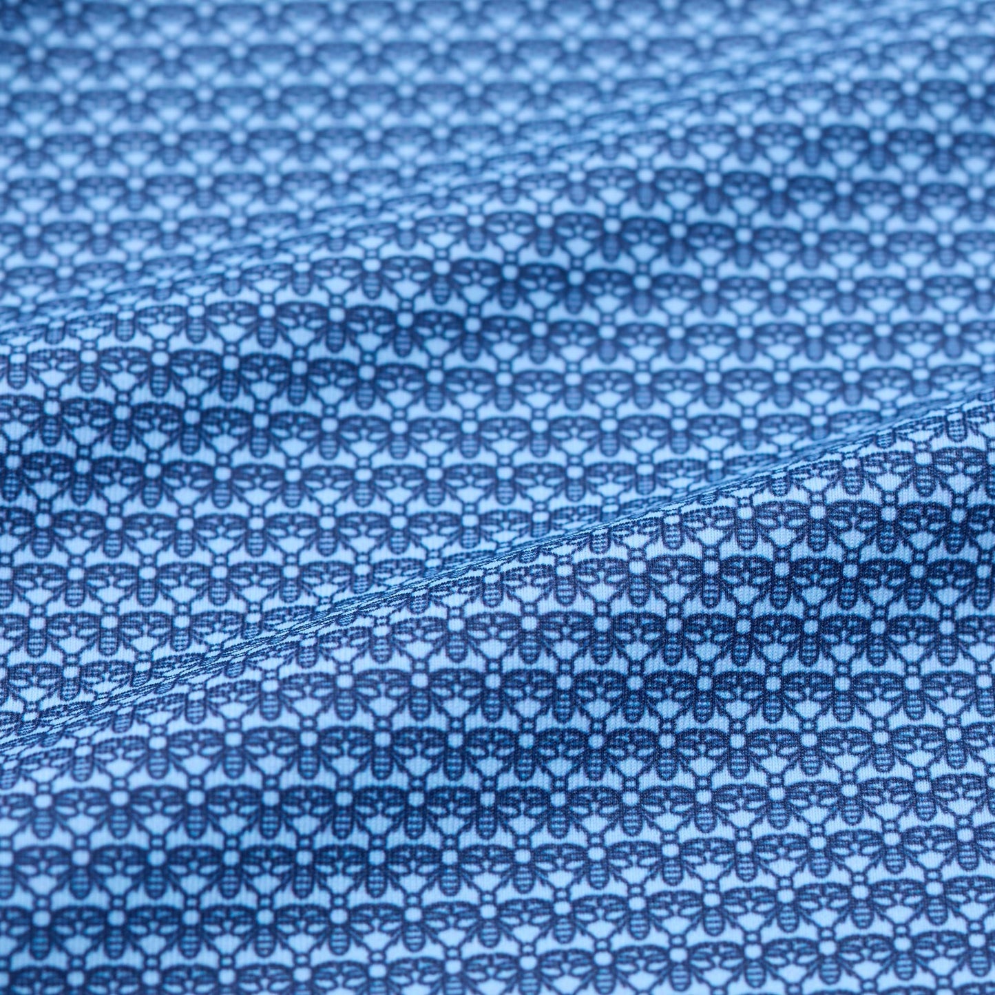 Close-up of blue fabric with a subtle bee pattern