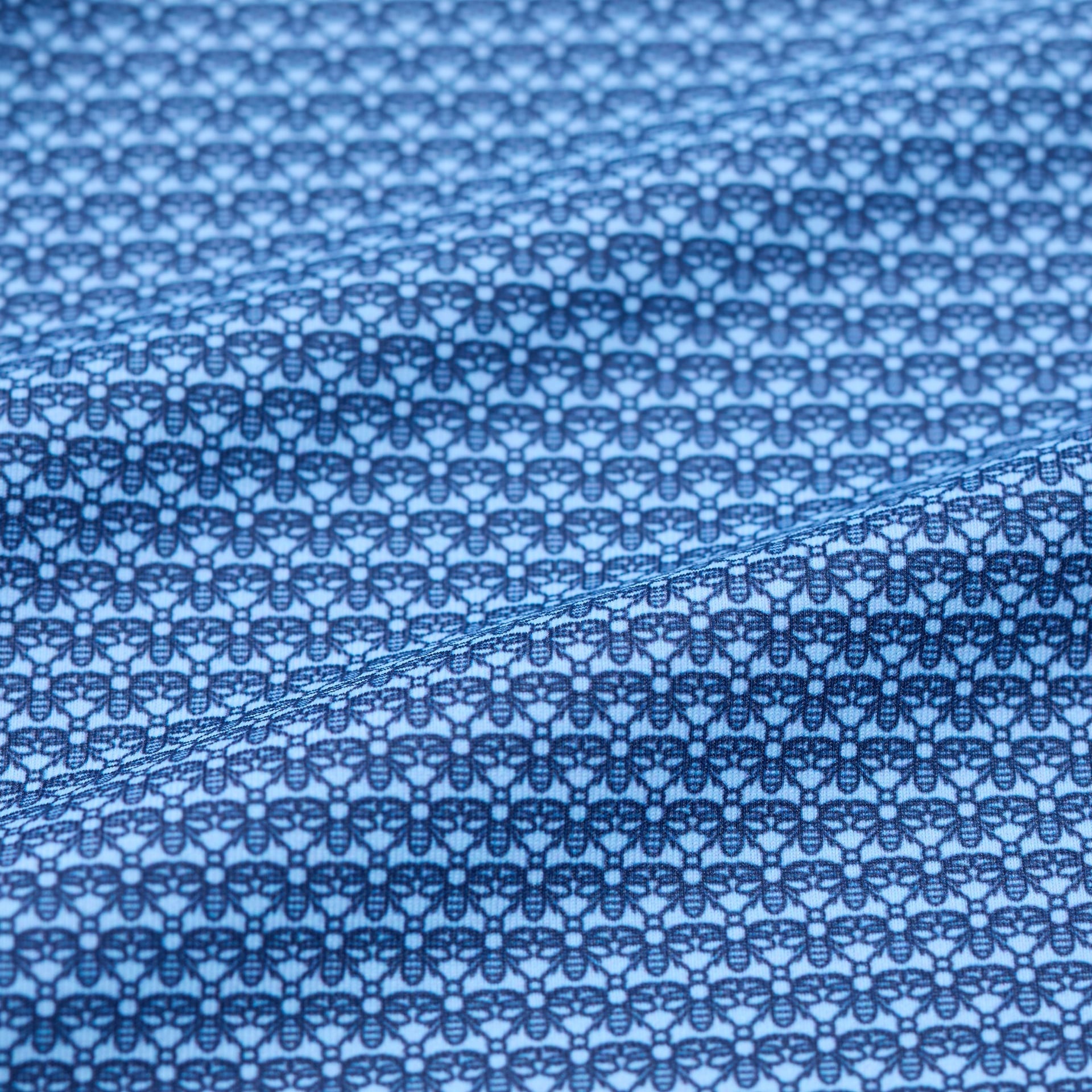 Close-up of blue fabric with a subtle bee pattern