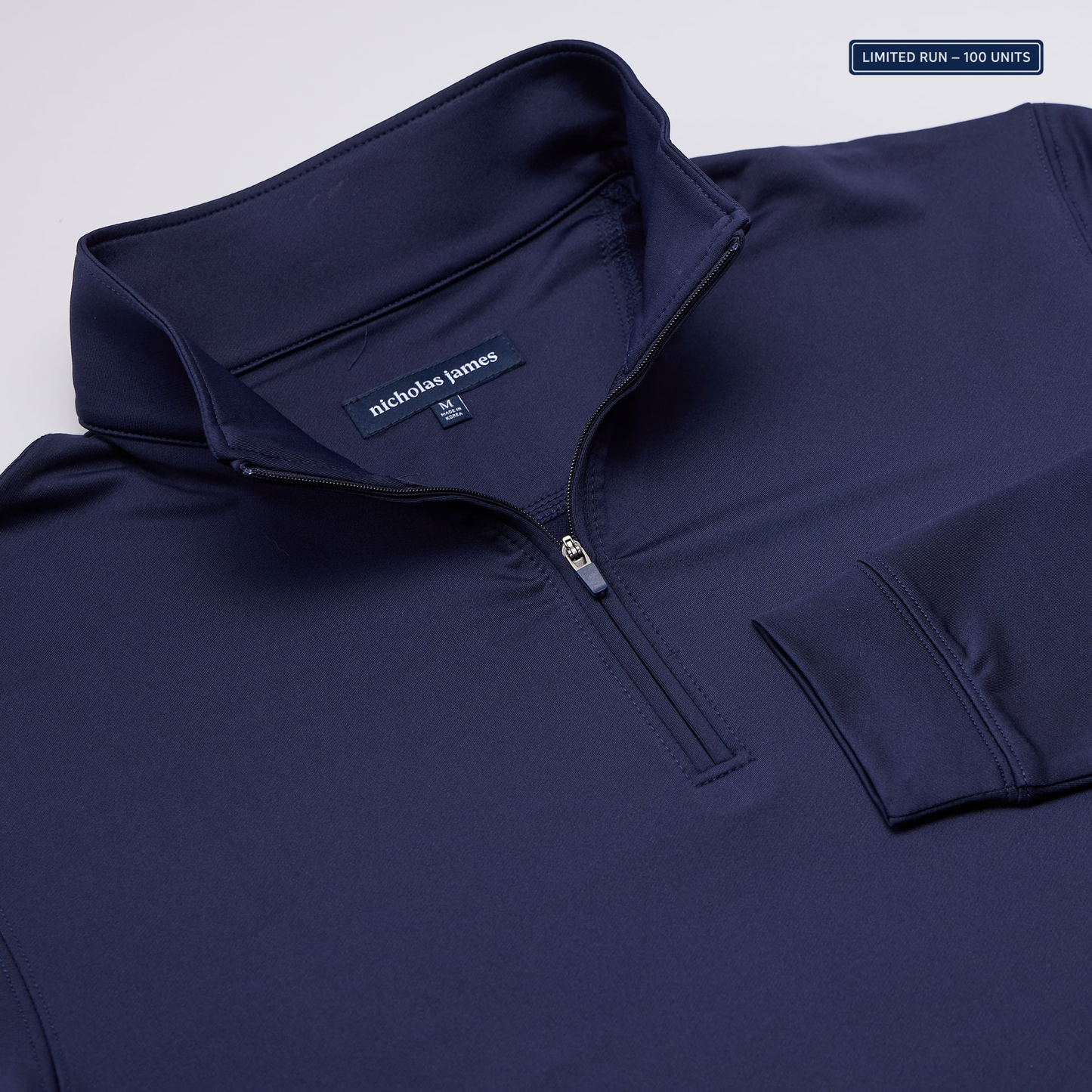 Navy blue pullover with nicholas james label on a light gray background